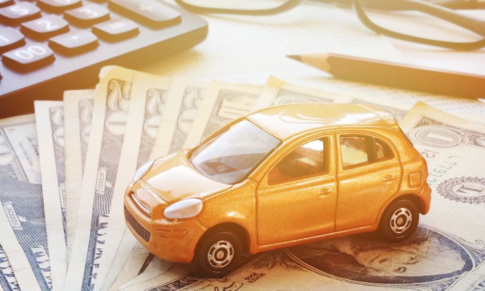 Business, finance, saving money, banking or car loan concept : Miniature car model, calculator, dollar money and saving account book or financial statement on office desk table