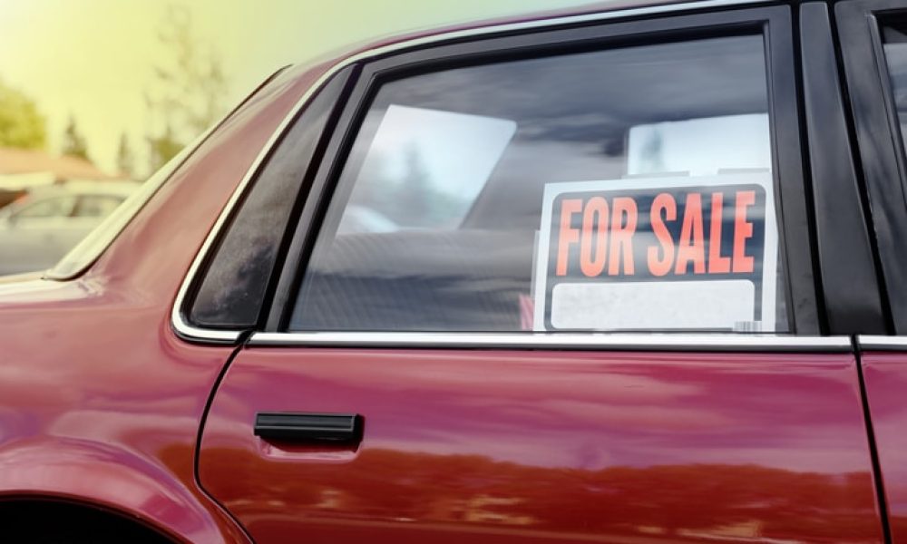 shiny car for sale in summer weather, parked with a red vibrant color exterior.